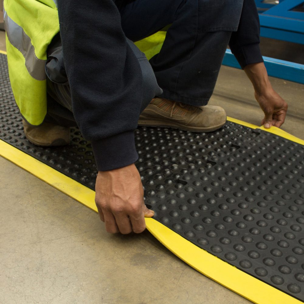 Worker-kneeling-and-connecting- together-a-black/yellow-Bubblemat- safety